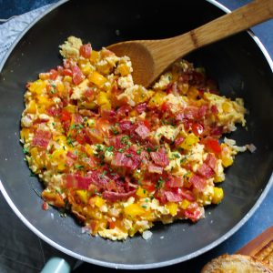An easy and healthy way to upgrade your scrambled eggs - peppers, tomatoes, cheese, bacon and a sprinkle of chilli make these Fiesta Scrambled Eggs a party on your plate.