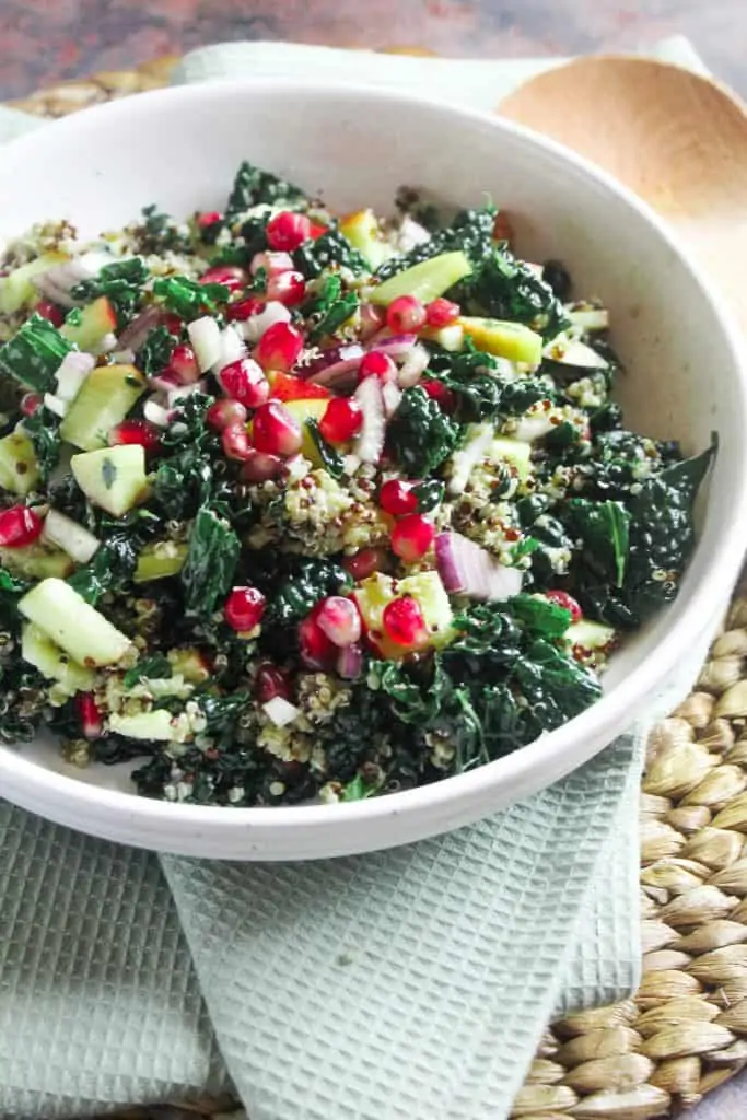 Bowl of kale and pomegranate salad with apple and quinoa.