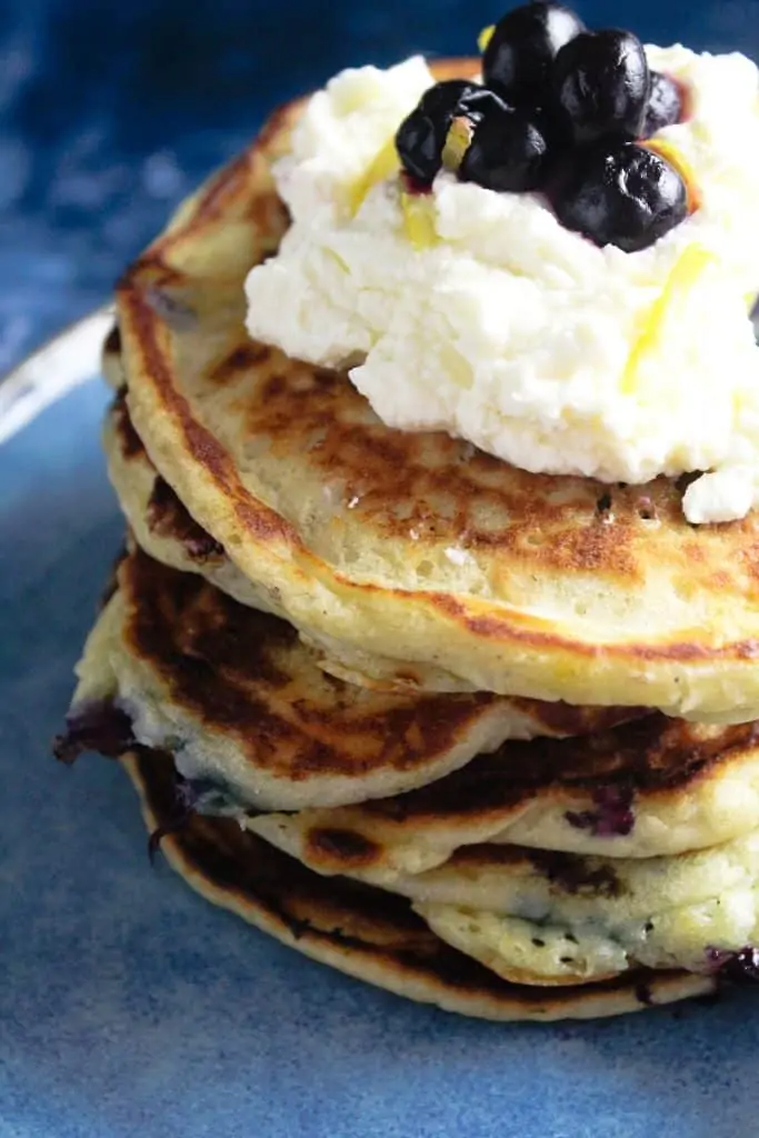 Close up of lemon blueberry pancakes topped with a dollop of lemon mascarpone cheese. 