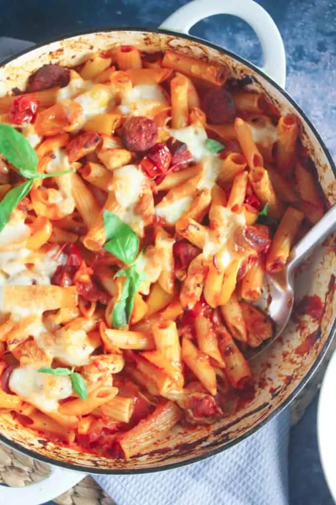 Close up of baked penne pasta in tomato sauce with chicken, chorizo and peppers. 