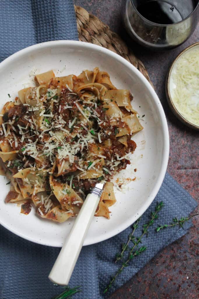 Aubergine ragu with pasta ribbons in a white bowl.