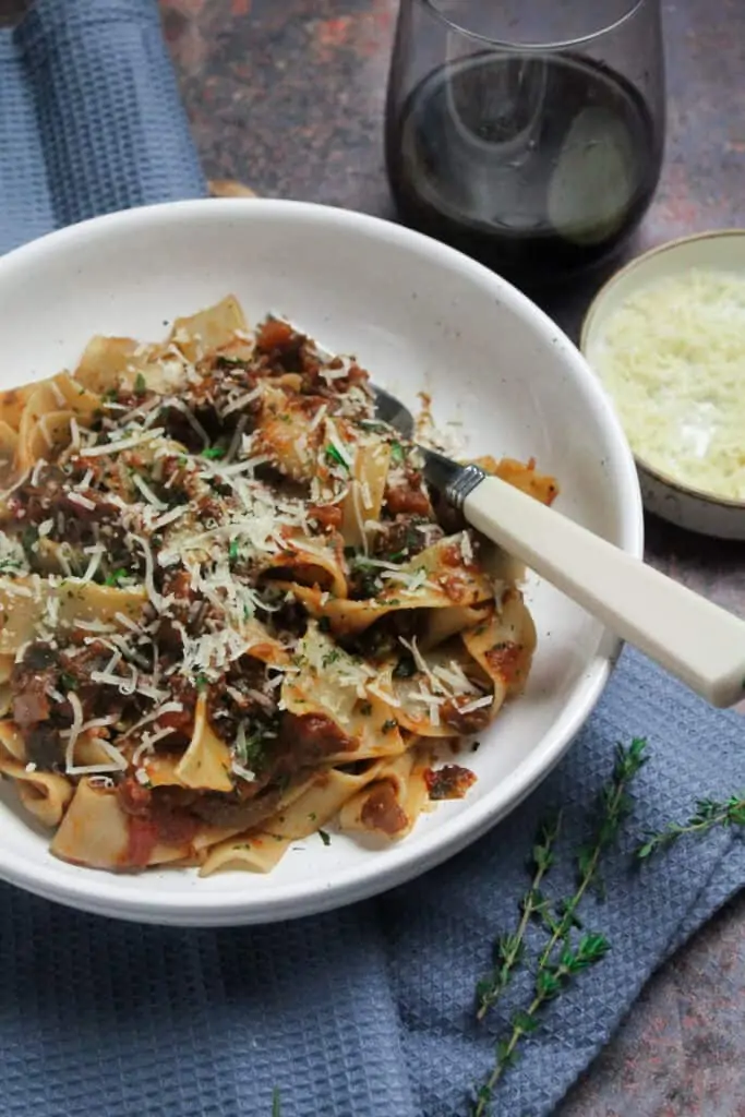 Vegetable ragu and pappardelle pasta in a white pasta bowl.