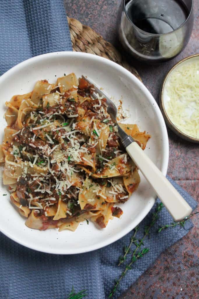 Pappardelle pasta tossed with rich aubergine ragu and topped with grated cheese and fresh herbs.