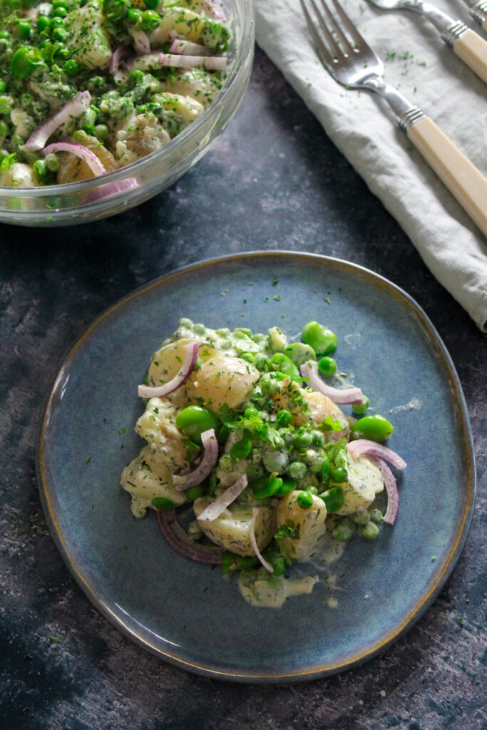 Potato Salad with peas, broad beans and a lemon dill dressing on a blue plate.