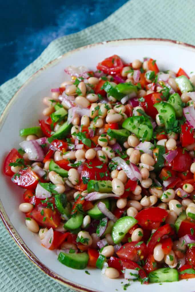 Salad of white beans with diced cucumber, tomato and red onion sprinkled with chopped parsley. 