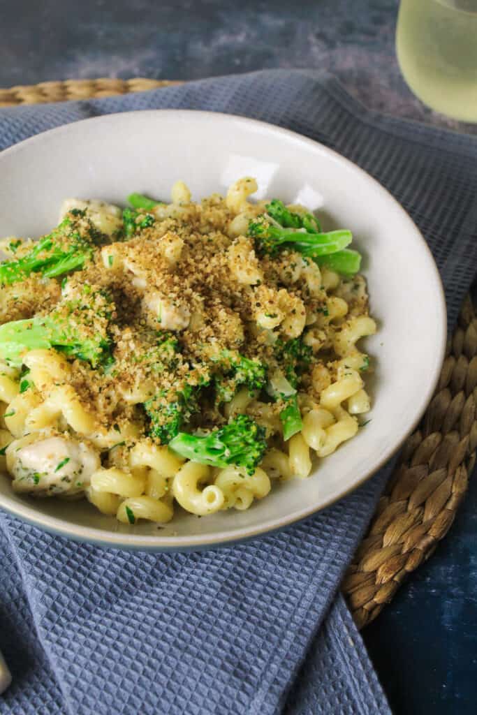 Bowl of pasta, chicken and broccoli in a creamy white sauce with breadcrumbs sprinkled on top. 