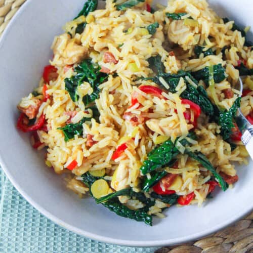 Bowl of rice stir fried with chicken, chorizo, leeks, red pepper and kale.
