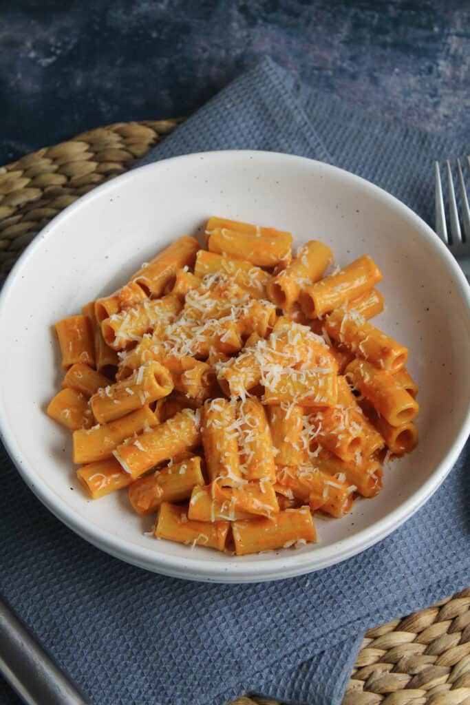 Rigatoni pasta shapes in a creamy red sauce sprinkled with grated cheese. 