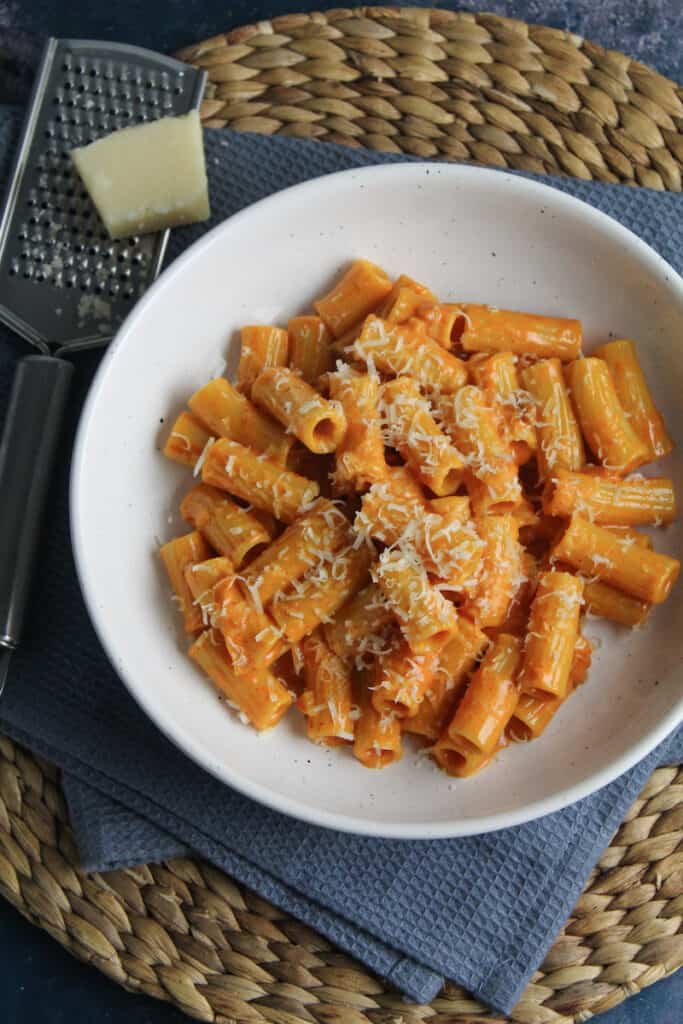 Rigatoni pasta in a creamy red gochujang sauce with sprinkled parmesan flakes. 