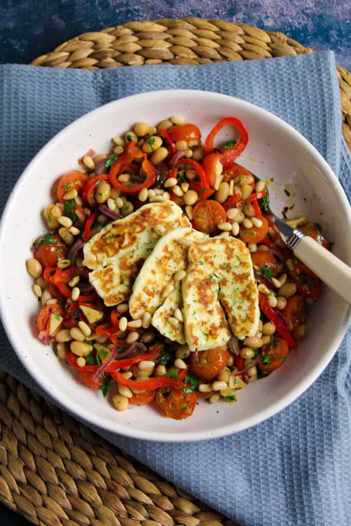 White serving bowl filled wit Halloumi Tomato Salad. 