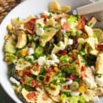 A bowl of pasta with chicken, zucchini and green onions.