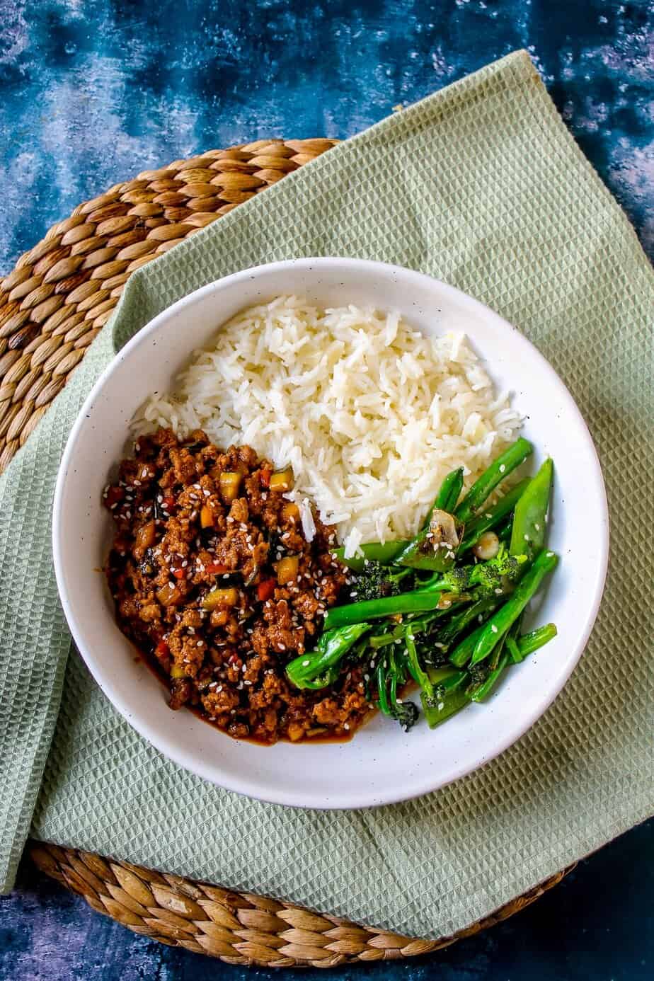 Savory Asian-inspired dish with ground beef, rice, and sautéed greens in a white bowl.