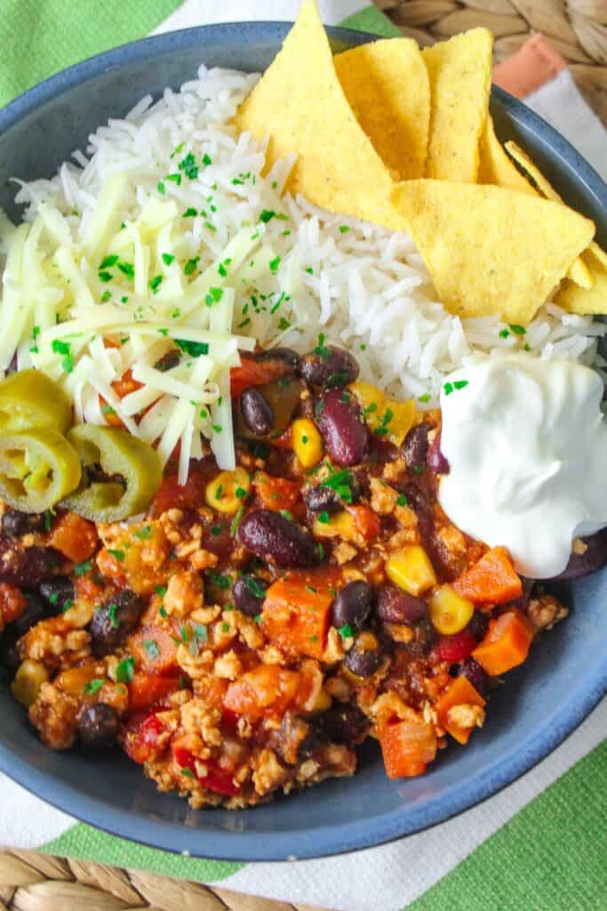 Close-up of a colorful chili dish topped with cheese, sour cream, and tortilla chips.