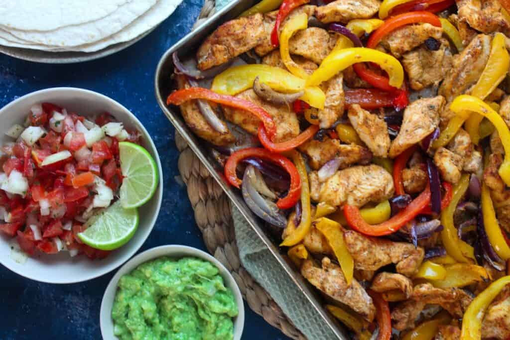 Delicious stir-fried chicken with colorful bell peppers, served with fresh salsa and guacamole for a.