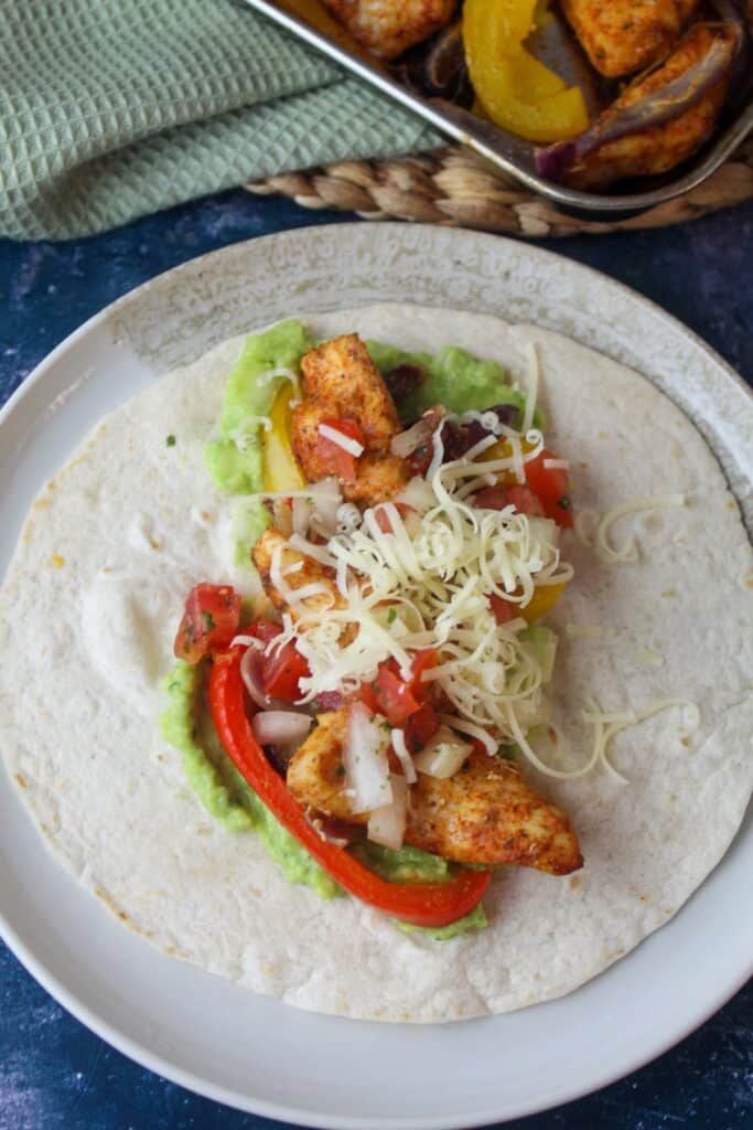 Chicken fajitas on soft tortilla with guacamole and cheese.