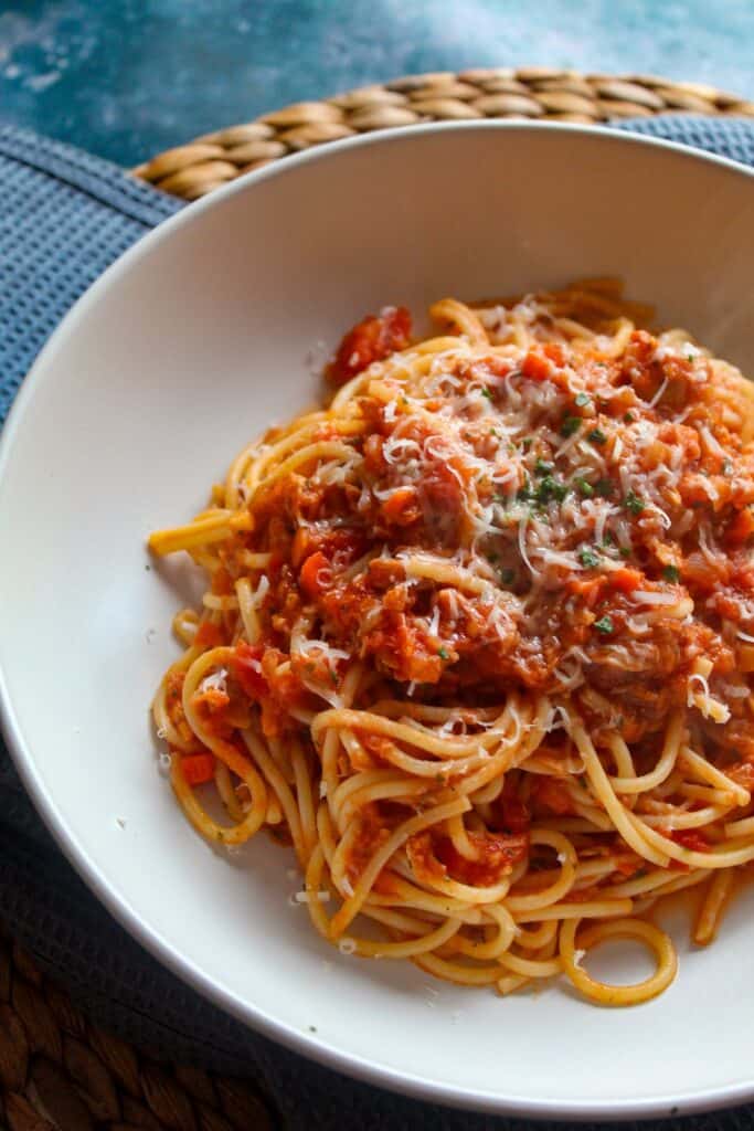 Delicious spaghetti with rich Tuna Bolognese sauce and grated cheese in a white bowl.